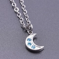 Macro view of silver crescent moon pendant with three blue rhinestones and cross chain - Steel Color + Necklace Chain