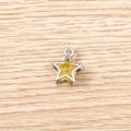Macro shot of a silver star pendant with yellow glitter texture on a light wood background - 5 Pieces / Silver & Yellow