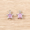 Detailed view of pink star charms with silver metal frames on light wood background - 5 Pieces / Silver Pink