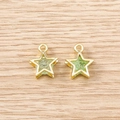 Close-up of gold star pendants with green stone inlay on a wooden background - 5 Pieces / Gold Green