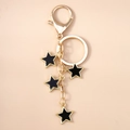 Dettaglio del portachiavi a stella dorato con pendenti in smalto nero e chiusura a moschettone - Stella Nera