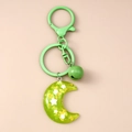 Detalle del llavero de luna en resina verde con pan de oro, estrella y cascabel a juego - Verde