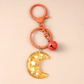 Detalle de llavero de luna de resina con lentejuelas de estrellas y campana roja - Naranja