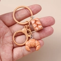 Detailed view of handmade resin baguette and croissant keychain held in hand - Flesh Color Croissant