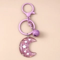 Detalle del llavero de luna en resina violeta con purpurina de estrellas y cascabel - Morado