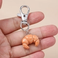 Détail d'un porte-clés croissant réaliste avec effet sucre glace et fermoir argenté - Croissant Argenté
