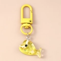 Détail d'un porte-clés baleine en résine jaune translucide avec des paillettes laser - Baleine Jaune