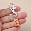 Close-up of creative baguette bread keychain held by hand with silver metal clasp detail - Silver Bread