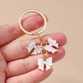 Detalle de tres colgantes de lazo de esmalte blanco con anillos dorados de zinc - Blanco