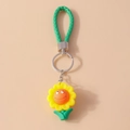 Makro-Detail eines lächelnden Sonnenblumen-Schlüsselanhängers mit grünem Webseil und Ring - Sonnenblume Lächeln / Gelb