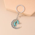 Close-up of vintage hollow crescent moon keychain with blue turquoise stone details - Green Stone Moon