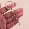 Detailed close-up of a sparkling rhinestone-studded golden cross keychain held in hand - Gold Cross