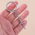 Dettaglio del portachiavi a croce argentato con strass tenuto in mano per misura - Croce Arrotondata Argento
