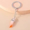 Detail of silver keyring with orange gradient hexagonal bullet pendant on peach stand - Orange and White