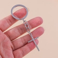 Close-up of a silver-tone cross keychain with sparkling rhinestones held in hand - Silver Cross