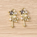 Detailed close-up of Y2K star charms with rhinestones and pearls on a light wood surface - Gold Black