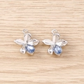 Close-up of silver-tone floral charms with a teardrop-shaped blue gemstone on wood background - Silver Blue