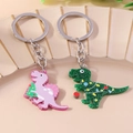 Detail von glitzernden Acryl-Dinosaurier-Schlüsselanhängern mit Weihnachtsbaum und Lichtern - Doppelter Dinosaurier