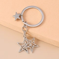 Detail van zilveren sterren sleutelhanger met holle pentagram hangers en punk kruis design - Holle Kleine Ster Stijl