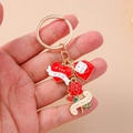 Detail of hand holding gold enamel MOM keychain with heart, envelope and rose charms - Red Envelope Flower