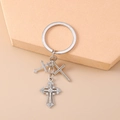Macro-opname van zilveren punk kruis sleutelhanger met witte strass op geometrische stand - Klein Kruis