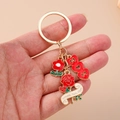 Dettaglio portachiavi in metallo dorato con ciondoli MOM a cuore e rosa in mano - Fiore del Cuore