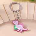Nahaufnahme von lila Acryl-Dinosaurier-Schlüsselanhänger mit Glitzer und Weihnachtsbaum-Muster - Rosa Dinosaurier