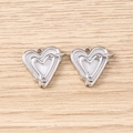 Close-up of dual heart-shaped silver pendants with white enamel and star accents - Silver