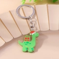 Detail eines grünen Glitzer Acryl Dinosaurier Schlüsselanhängers mit roter Weihnachtsmütze - Hellgrüner Dinosaurier