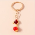 Dettaglio di un portachiavi dorato con ciondolo in smalto rosso e perla sferica - Coniglio Lanterna Rosso