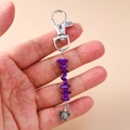 Detail of silver turtle keychain with purple natural stone beads held in hand - Purple Stone Turtle