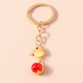 Primo piano di un portachiavi a forma di uccello dorato con perla rossa e anello metallico - Coniglio Lanterna Giallo