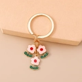 Dettaglio di un portachiavi a fiore dorato con petali in smalto rosa su base beige - Rosa