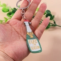 Detailed close-up of champagne bottle keychain with green glitter and Christmas hat - Glitter Champagne Bottle