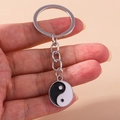 Detail shot of Yin Yang pendant keychain in polished silver metal with enamel finish - Bagua Tai Chi