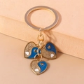 Macro shot of gold-plated triple heart keychains with blue and white yin-yang patterns - Blue Tai Chi Heart