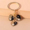Detailed macro view of gold-plated Yin Yang heart charms with black enamel and gold glitter - Black Tai Chi Heart