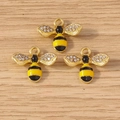 Three golden enamel bee pendants with sparkling white rhinestones on a wooden background - 10 Pieces Pack / Black and Yellow Bee