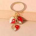 Macro shot of heart-shaped pendants with red enamel and golden glitter on key ring - Red Tai Chi Heart