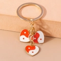 Vue macro de pendentifs cœur dorés avec détails en émail Tai Chi Yin Yang rouge et blanc - Cœur Tai Chi Orange
