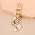 Golden keychain with pearl bow, sun medallion and heart charm on beige geometric blocks - Clock Bowknot Style