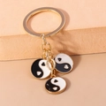 Détail d'un porte-clés Tai Chi doré avec motif yin yang en cœur et anneaux métalliques - Tai Chi Noir