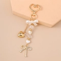 Detail of a golden heart keychain with white pearl bow and rhinestone heart charms - Gold Heart Bow