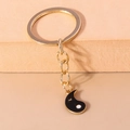 Détail d'un porte-clés yin yang doré avec breloque cœur en émail noir sur supports - Moitié Yin Noir