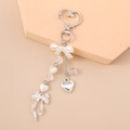 Detailed shot of pearlescent bow and silver heart pendant on a stylish keychain charm - Silver Heart Bow