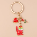 Detail eines goldenen LOVE-Schlüsselanhängers mit Emaille-Rose und Herzanhänger auf Rosa - Herz Regenbogen Love