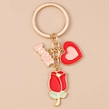 Détail d'un porte-clés doré avec rose rouge, cœur et breloques LOVE sur fond rose - Love Cœur Rose
