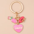 Détail d'un porte-clés doré avec pendentifs émaillés en forme de rose et de cœur XOXO - Lèvres Xoxo Cœur