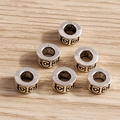 Detalle macro de seis cuentas cilíndricas de plata vintage sobre fondo de madera - Estilo de Patrón Geométrico Cilíndrico