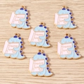 Detail von 6 hellblauen Dino-Anhängern mit rosa Happy Time Buch für DIY-Bastelarbeiten - 10er Pack / Lesender Dinosaurier
